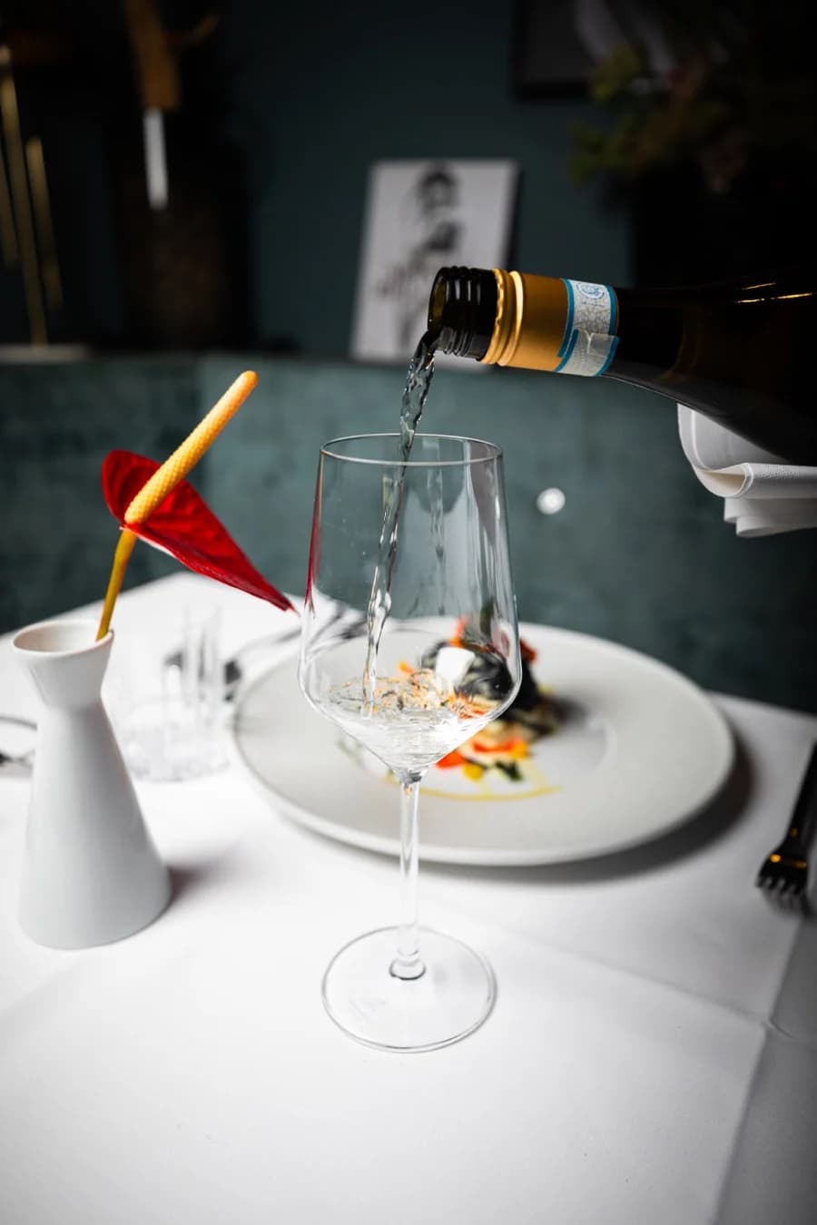 Weißwein wird am Tisch eingeschenkt