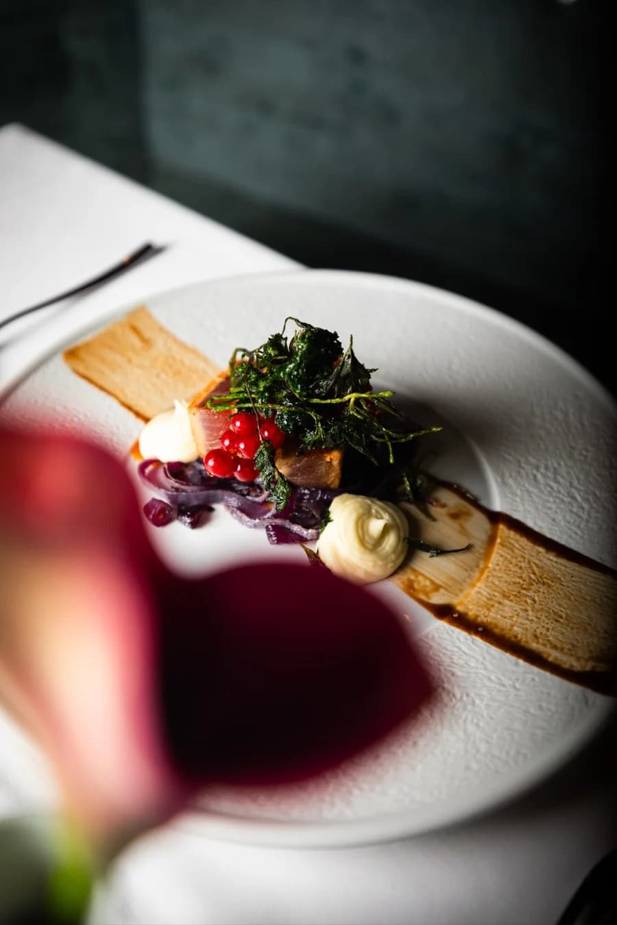 Vorspeise mit Kräutern, Johannisbeeren und Saucen, im Vordergrund eine Calla