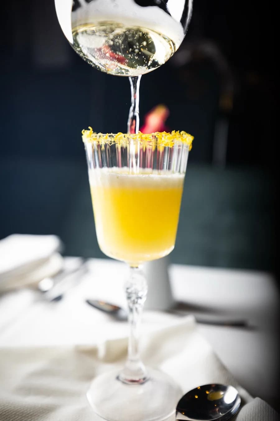 Champagner wird in einen Cocktail mit Zuckerrand gegossen