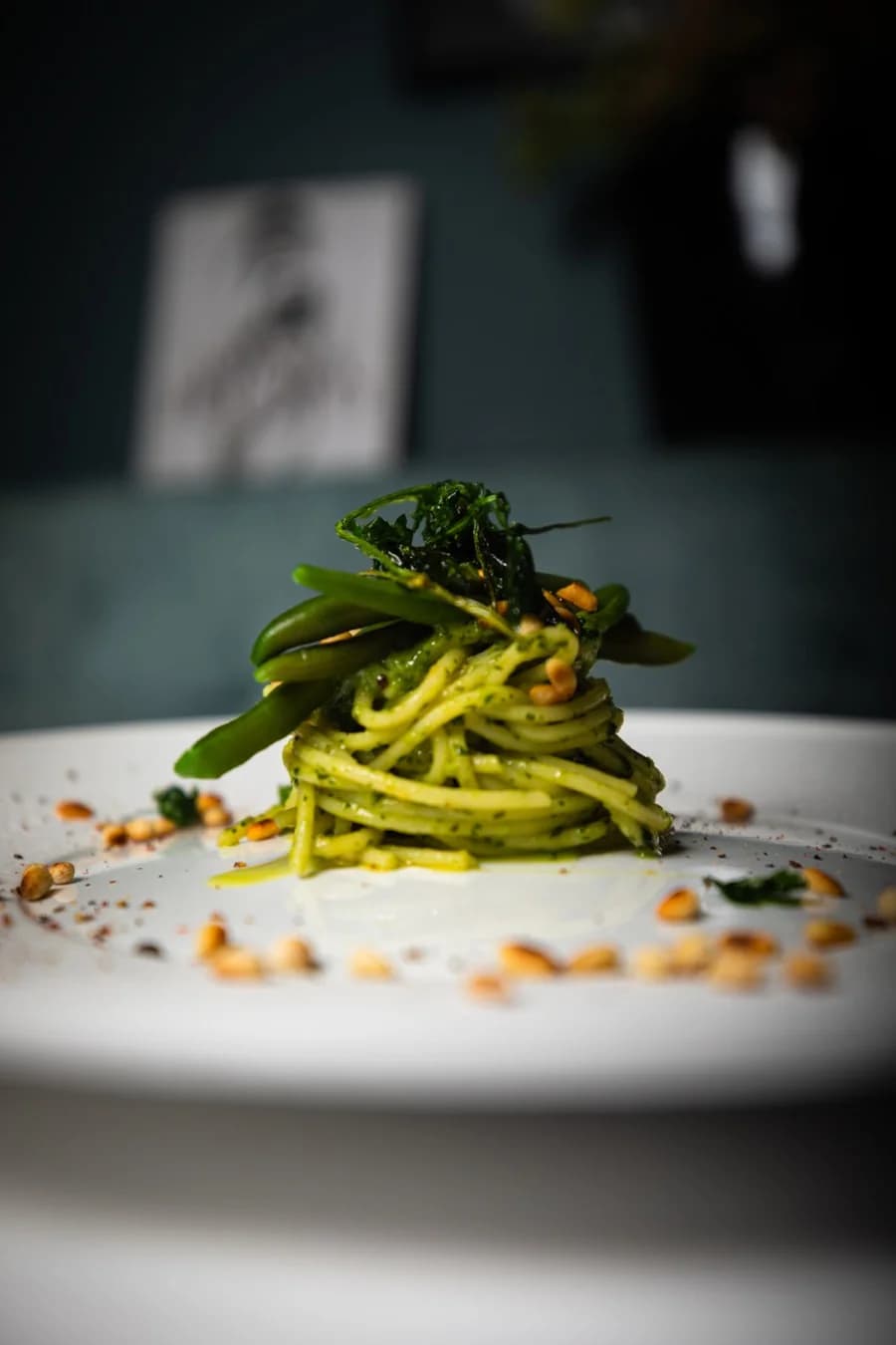 Grüne Tagliolini mit Pesto und Pinienkernen auf weißem Teller