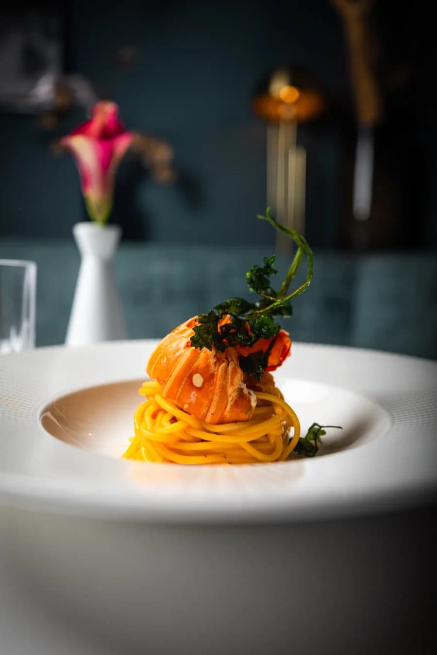 Spaghetti mit Lachs, dahinter eine Calla in weißer Vase