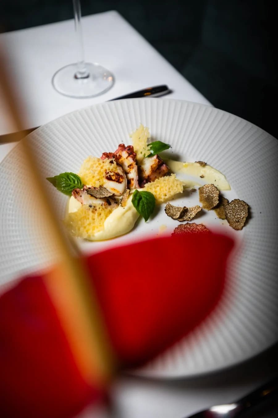 Gericht mit Trüffel und Parmesanchips, im Vordergrund eine rote Blüte