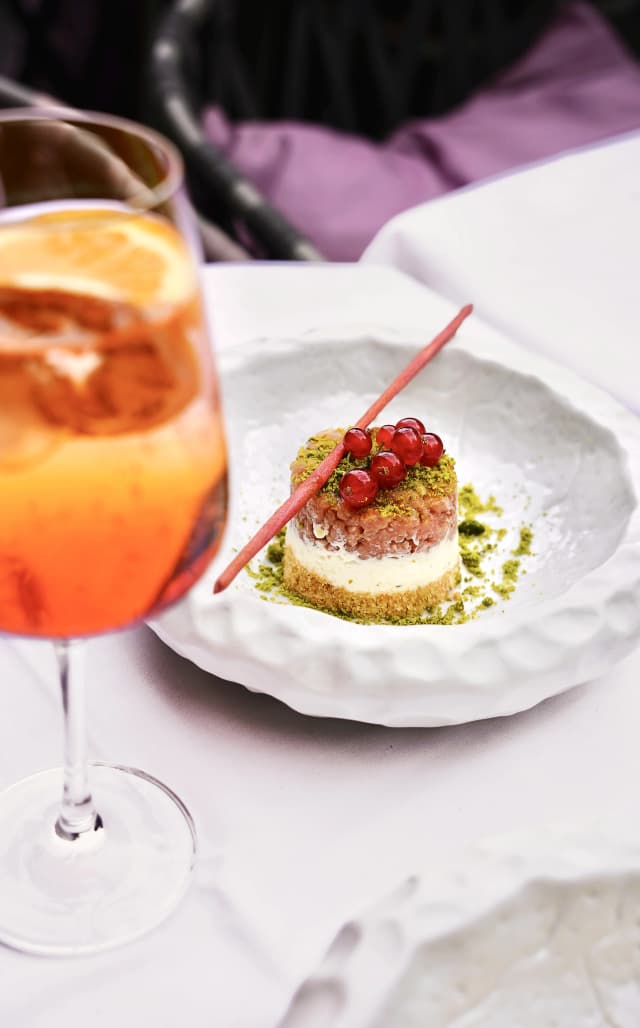 Bellucci Berlin – Pistazien-Cheesecake mit Johannisbeeren neben einem Aperol Spritz auf der Terrasse