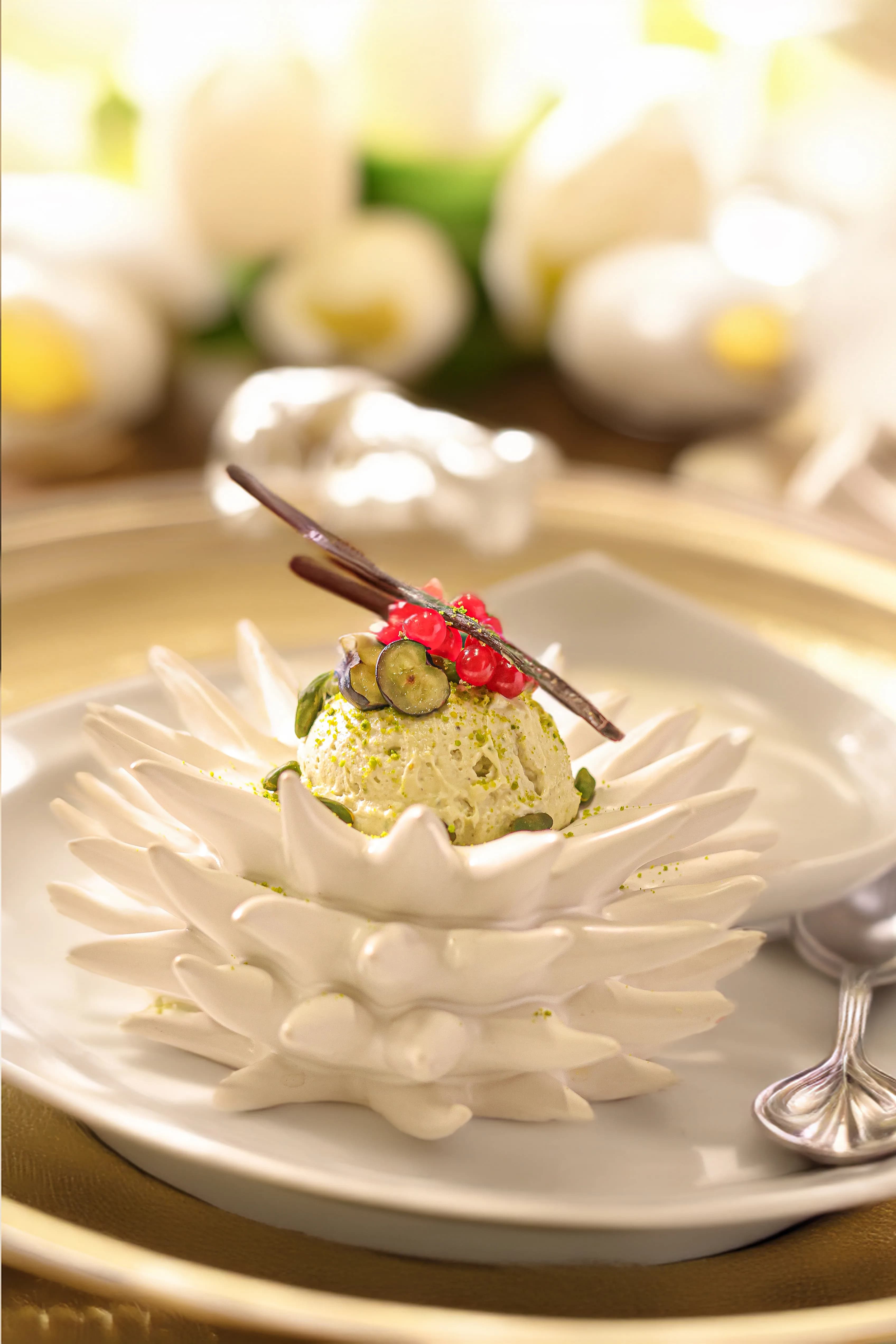 Bellucci Berlin – Pistazien-Mousse auf kunstvollem Porzellanteller mit goldener Tischdekoration